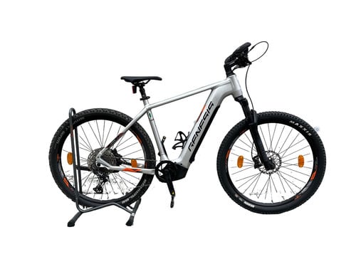 Silbernes E-Bike auf einem Ständer mit schwarzen Reifen und orangefarbenen Details.