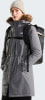 Frau in grauer Winterjacke mit Pelzkragen und beigefarbener Mütze mit Muster.