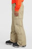 Ein Mann in beige Skihose mit orangefarbener Jacke und schwarzen Stiefeln.
