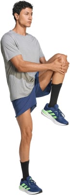 Ein Mann in einem grauen T-Shirt und blauen Shorts dehnt sein Bein. Ein Mann in einem grauen T-Shirt und blauen Shorts dehnt sein Bein.