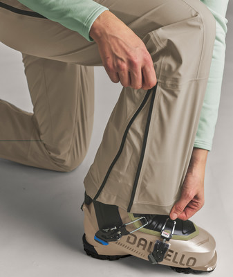 Eine Person schließt den Reißverschluss einer Outdoor-Hose an einem Skischuh. Eine Person schließt den Reißverschluss einer Outdoor-Hose an einem Skischuh.