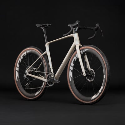 Ein beiges Gravelbike mit schwarzem Lenker und braunen Reifen vor schwarzem Hintergrund. Ein beiges Gravelbike mit schwarzem Lenker und braunen Reifen vor schwarzem Hintergrund.