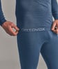 Ein Mann zieht eine blaue Thermounterhose mit ORTOVOX-Logo am Bund herunter.
