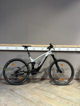 Ein silbernes Genesis E-Mountainbike steht auf einem Holzboden.