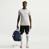 Ein Mann hält eine Tasche und trägt Nike-Fußballkleidung.