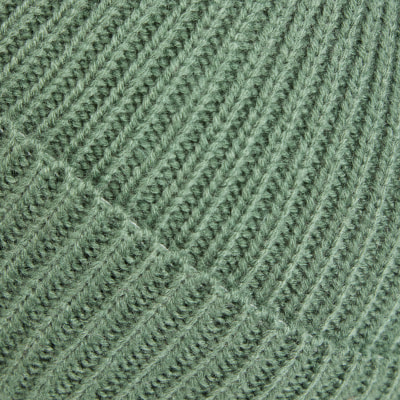 Detail einer dunkelgrünen Strickware mit diagonalem Muster.
