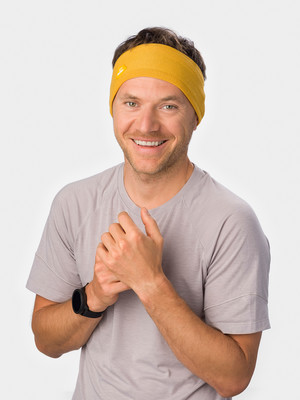 Ein Mann mit einem Stirnband und einer Uhr lächelt.