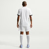 Ein Mann in einem weißen Fußballtrikot und Shorts von hinten.