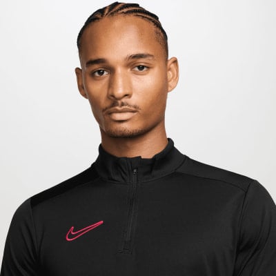 Ein Mann in einem schwarzen Oberteil mit Nike-Logo und einem pinken Logo auf der Brust. Ein Mann in einem schwarzen Oberteil mit Nike-Logo und einem pinken Logo auf der Brust.
