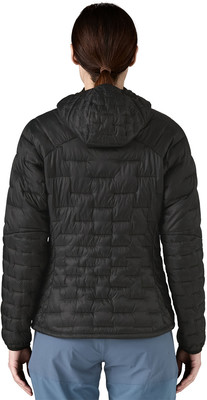 Rückansicht einer Person in einer schwarzen Steppjacke mit Kapuze und blauer Hose. Rückansicht einer Person in einer schwarzen Steppjacke mit Kapuze und blauer Hose.