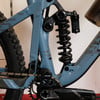 Hinterer Stoßdämpfer und Federung eines Mountainbikes mit blauem Rahmen.