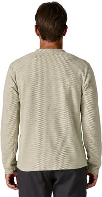 Rückansicht eines Mannes in einem beigen Pullover mit langen Ärmeln und dunkler Hose. Rückansicht eines Mannes in einem beigen Pullover mit langen Ärmeln und dunkler Hose.