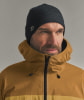 Ein Mann mit dunkler Mütze und brauner Kapuzenjacke blickt zur Seite.