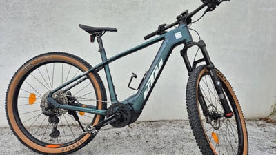 Ein grünes KTM E-Bike mit braunen Reifen vor einer weißen Wand. Ein grünes KTM E-Bike mit braunen Reifen vor einer weißen Wand.