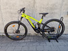 Grünes E-Mountainbike auf einem Ständer vor einer Betonwand.