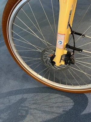 Detail eines Fahrrad-Vorderrads mit Scheibenbremse an einer gelben Gabel. Detail eines Fahrrad-Vorderrads mit Scheibenbremse an einer gelben Gabel.