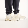 Beige Sneaker mit dunkelblauen Jogginghosen auf weißem Hintergrund.