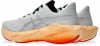 Weiße Laufschuhe mit orangefarbener Sohle und schwarzen Schnürsenkeln.