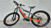 Graues E-Bike mit orangefarbenen Akzenten und breiten Reifen.