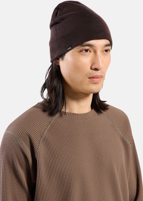 Ein Mann mit langen Haaren trägt eine braune Mütze und ein Waffel-Shirt.