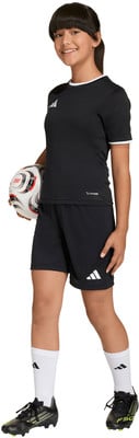 Ein Mädchen in einem schwarzen Fußballtrikot und Shorts hält einen Fußball.