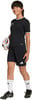 Ein Mädchen in einem schwarzen Fußballtrikot und Shorts hält einen Fußball.