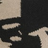 Detail eines Strickmusters mit schwarzem und beigem Fleckenmuster, das an Leopardenfell erinnert.