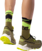 Grüne Laufsocken mit der Aufschrift ROAD und Dynafit-Schuhe auf weißem Hintergrund.