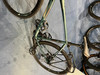 Ein grünes Fahrrad mit Taschen hängt an der Wand, Detail von Rad und Rahmen.
