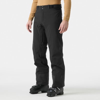 Ein Mann in Skihose und Skischuhen steht vor weißem Hintergrund. Ein Mann in Skihose und Skischuhen steht vor weißem Hintergrund.
