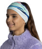 Mädchen mit buntem Stirnband und lila Fleece-Kleidung.