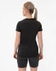 Frau in schwarzem T-Shirt und dunkler Hose mit Pferdeschwanz.