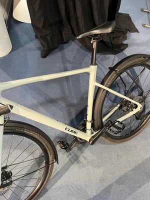 Ein hellgrünes Cube-Fahrrad mit Schutzblechen und Ständer auf einem blauen Teppich. Ein hellgrünes Cube-Fahrrad mit Schutzblechen und Ständer auf einem blauen Teppich.