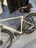 Ein hellgrünes Cube-Fahrrad mit Schutzblechen und Ständer auf einem blauen Teppich.