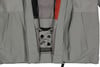 Detail einer Jacke mit Taschen und Druckknöpfen in Grau- und Orangetönen.
