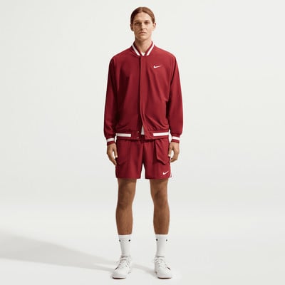 Ein Mann in einer roten Nike Bomberjacke und Shorts mit weißen Streifen. Ein Mann in einer roten Nike Bomberjacke und Shorts mit weißen Streifen.