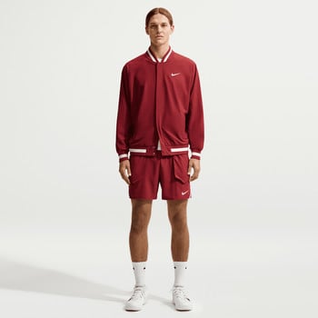 Ein Mann in einer roten Nike Bomberjacke und Shorts mit weißen Streifen.