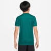 Rückansicht eines Jungen in einem dunkelgrünen Kurzarmshirt und schwarzer Hose.