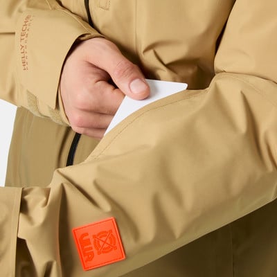 Egy férfi egy kártyát tesz be a Helly Tech logós kabát zsebébe. Egy férfi egy kártyát tesz be a Helly Tech logós kabát zsebébe.