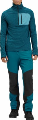 Mann in dunkelblauem Reißverschluss-Pullover und blauer Hose mit schwarzen Einsätzen.