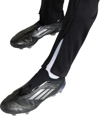 Adidas F50 Fußballschuhe mit schwarzer Hose und Reißverschluss am Bein.