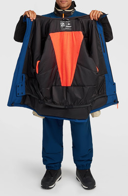Ein Mann betrachtet das Innere einer blauen Daunenjacke mit orangenem Detail. Ein Mann betrachtet das Innere einer blauen Daunenjacke mit orangenem Detail.