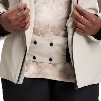 Detail einer beigen Jacke mit schwarzen Knöpfen und gemustertem Einsatz.