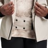Detail einer beigen Jacke mit schwarzen Knöpfen und gemustertem Einsatz.