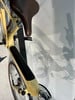 Rahmen- und Sitzdetail eines gelben Fahrrads mit Schatten an der Wand.