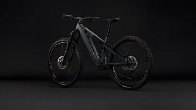 Ein dunkelgraues E-Mountainbike mit Federung steht vor einem schwarzen Hintergrund. Ein dunkelgraues E-Mountainbike mit Federung steht vor einem schwarzen Hintergrund.