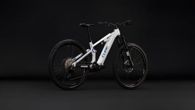 Ein modernes weißes Cube Mountain E-Bike mit Federung, das auf schwarzem Hintergrund steht.