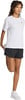Eine Frau in einem weißen Shirt und schwarzen Shorts dehnt ihr Bein.