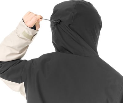 Rückansicht einer Person, die den Kordelzug an der Kapuze einer Jacke verstellt.