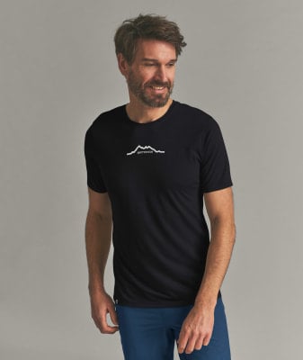 Ein Mann in einem schwarzen T-Shirt mit Bergmotiv und blauer Hose. Ein Mann in einem schwarzen T-Shirt mit Bergmotiv und blauer Hose.